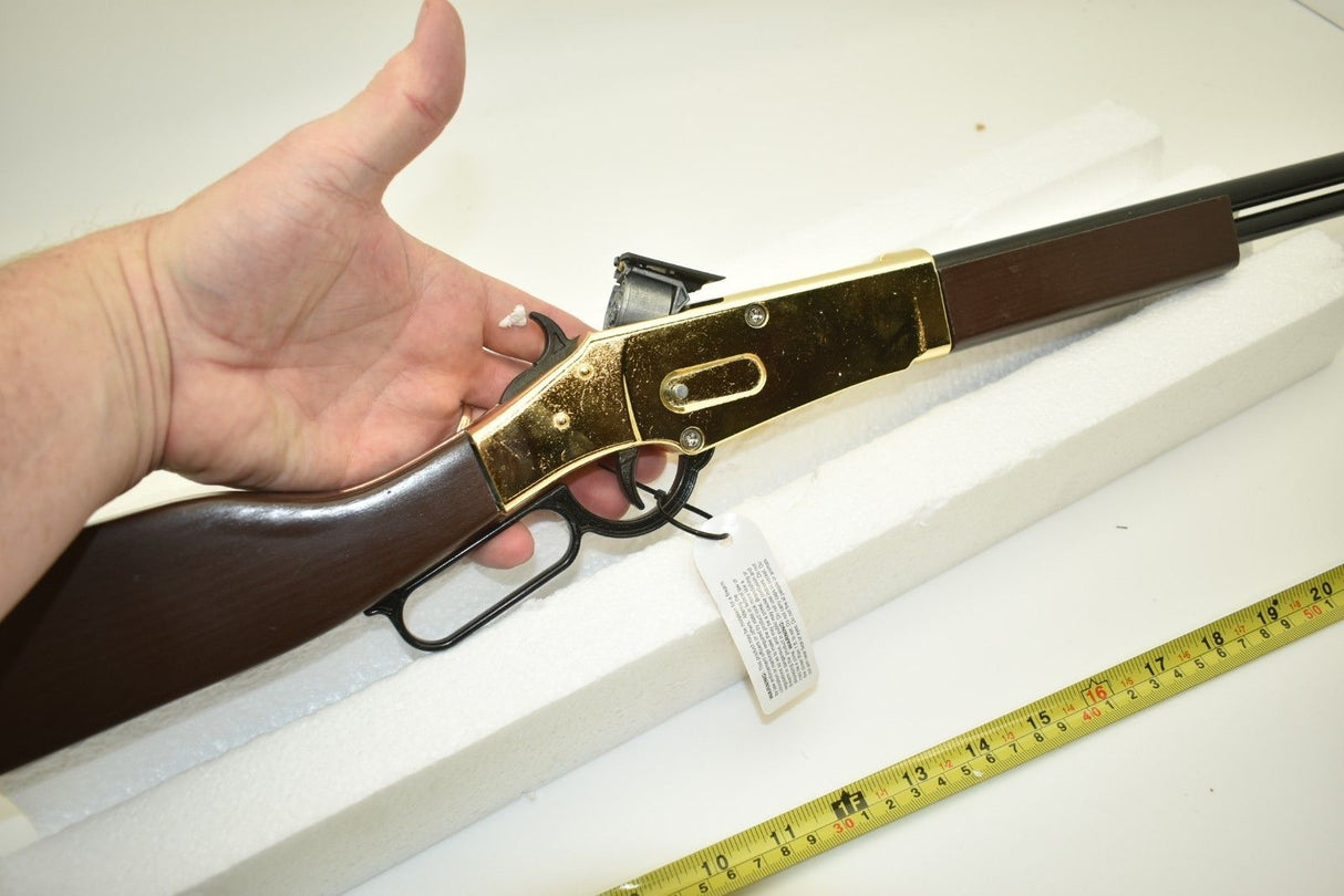 Toy rifle with wooden stock and gold-colored metal parts, resting on white surface for Parris Toys 2703C