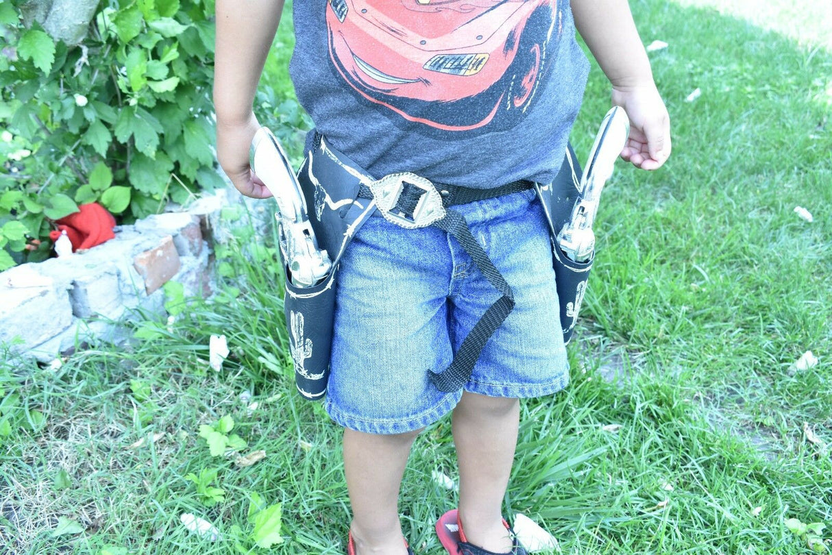 Child wearing a holster with two toy pistols on a grassy lawn for Parris Toys 5506