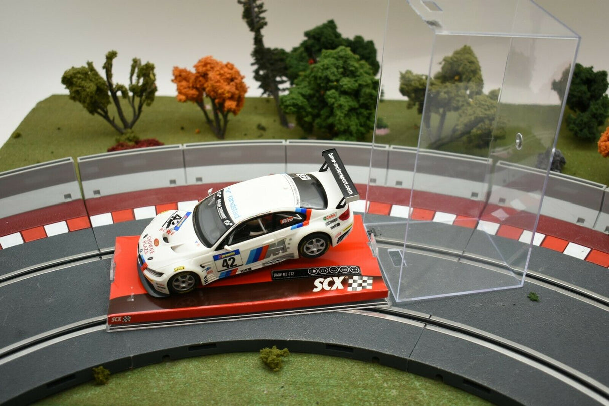White race car on a miniature racetrack with green trees in the background for SCX A10156X3U0