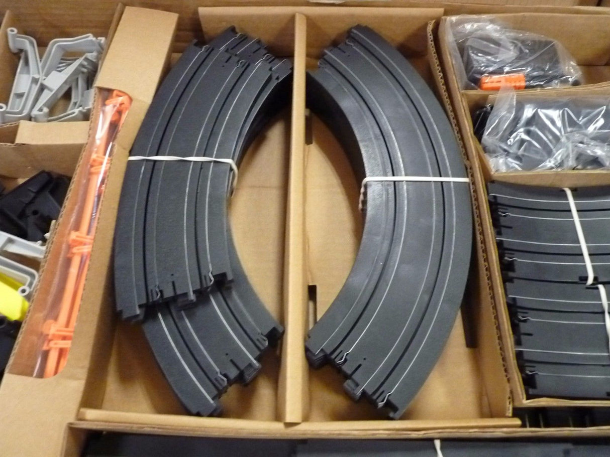 Curved black race track pieces laid out in a cardboard box for Aurora / AFX / Tomy 9115M