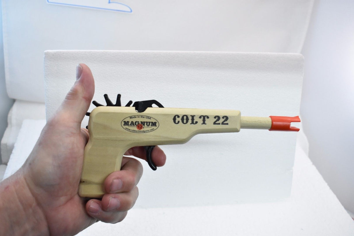 Toy Colt 22 pistol with green ammo, held in hand for Magnum Rubber Band Guns GL2C22