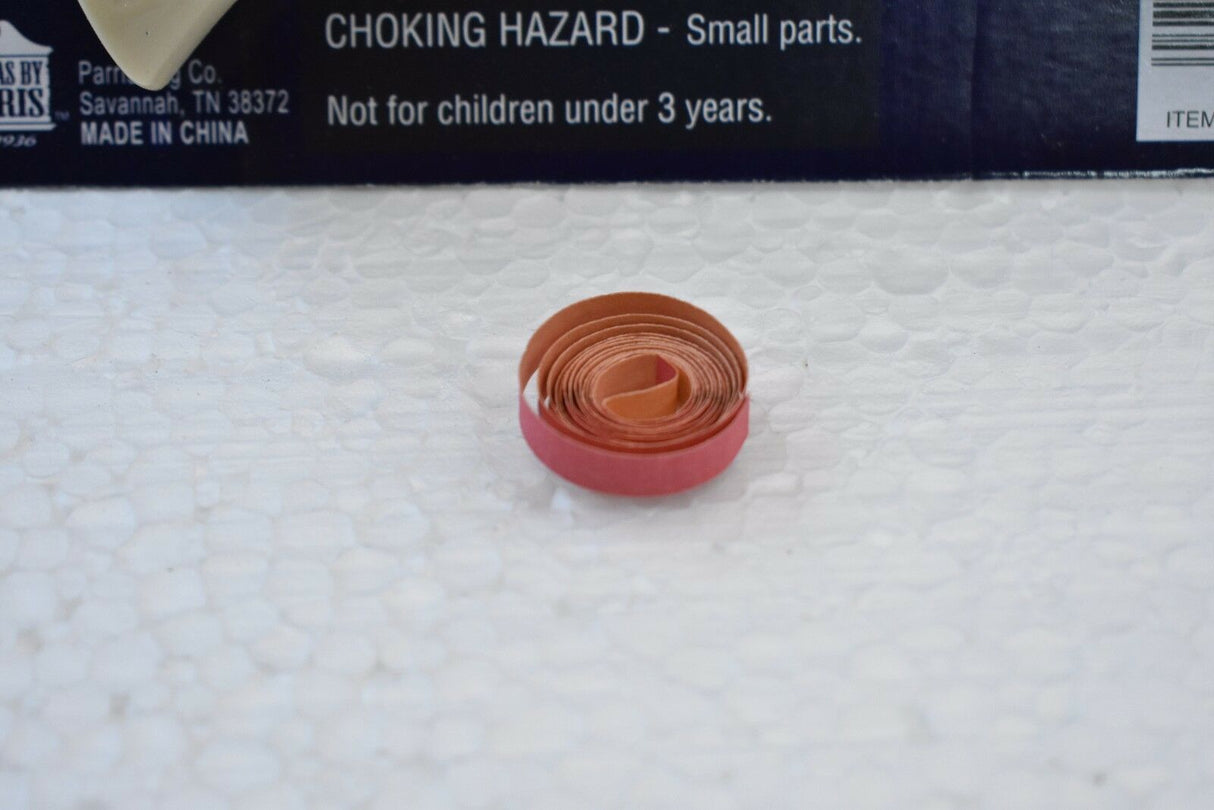 Small, coiled, reddish-brown plastic piece on a white surface for Parris Toys 0652