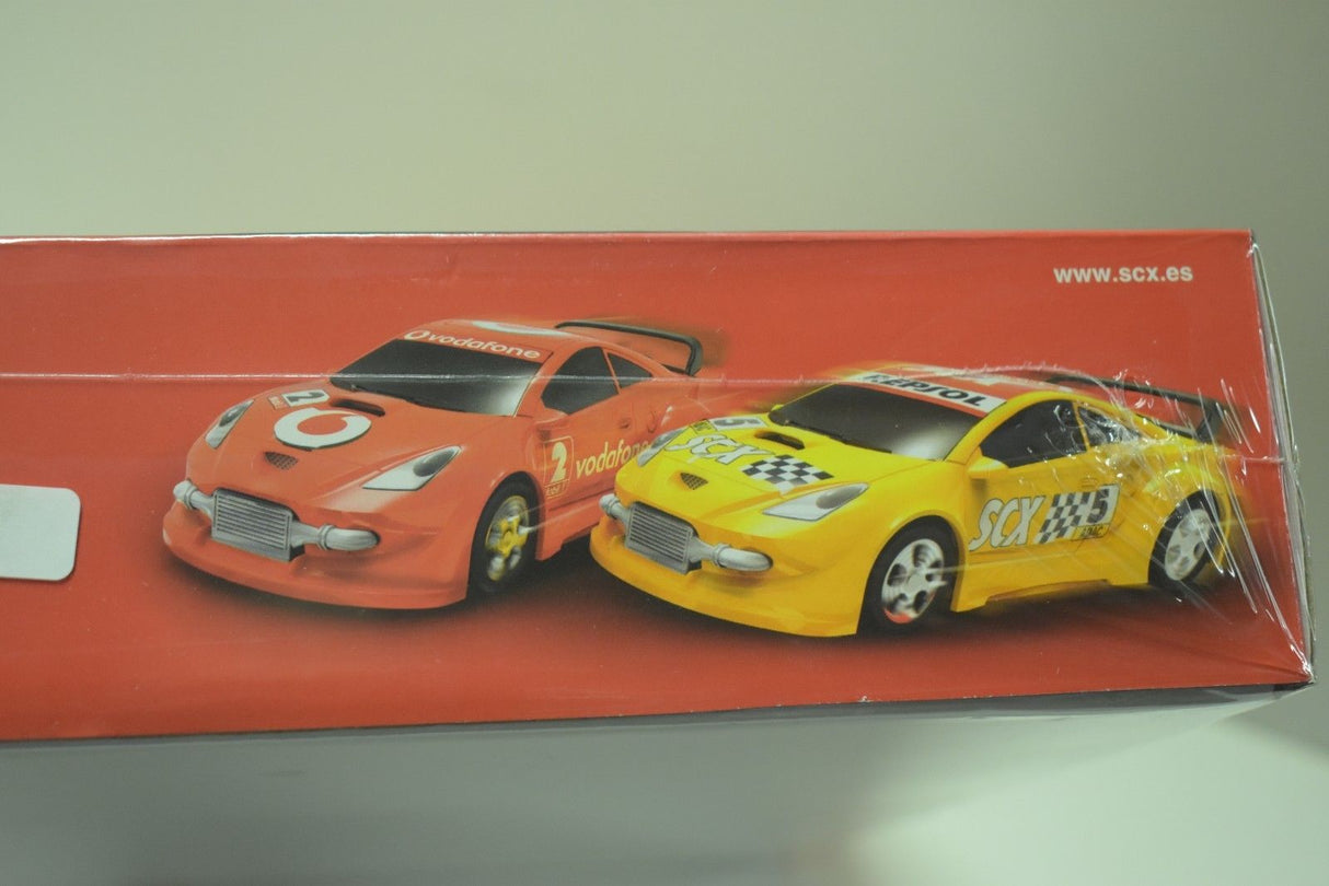 Two race cars, one orange and one yellow, displayed on a red box for SCX Compact C10125X5U0