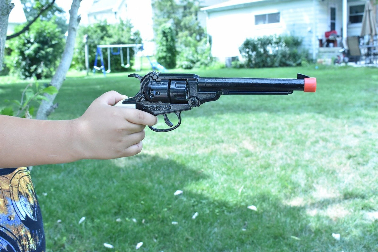 Child holding a black toy revolver with a red tip outdoors for Parris Toys 0652