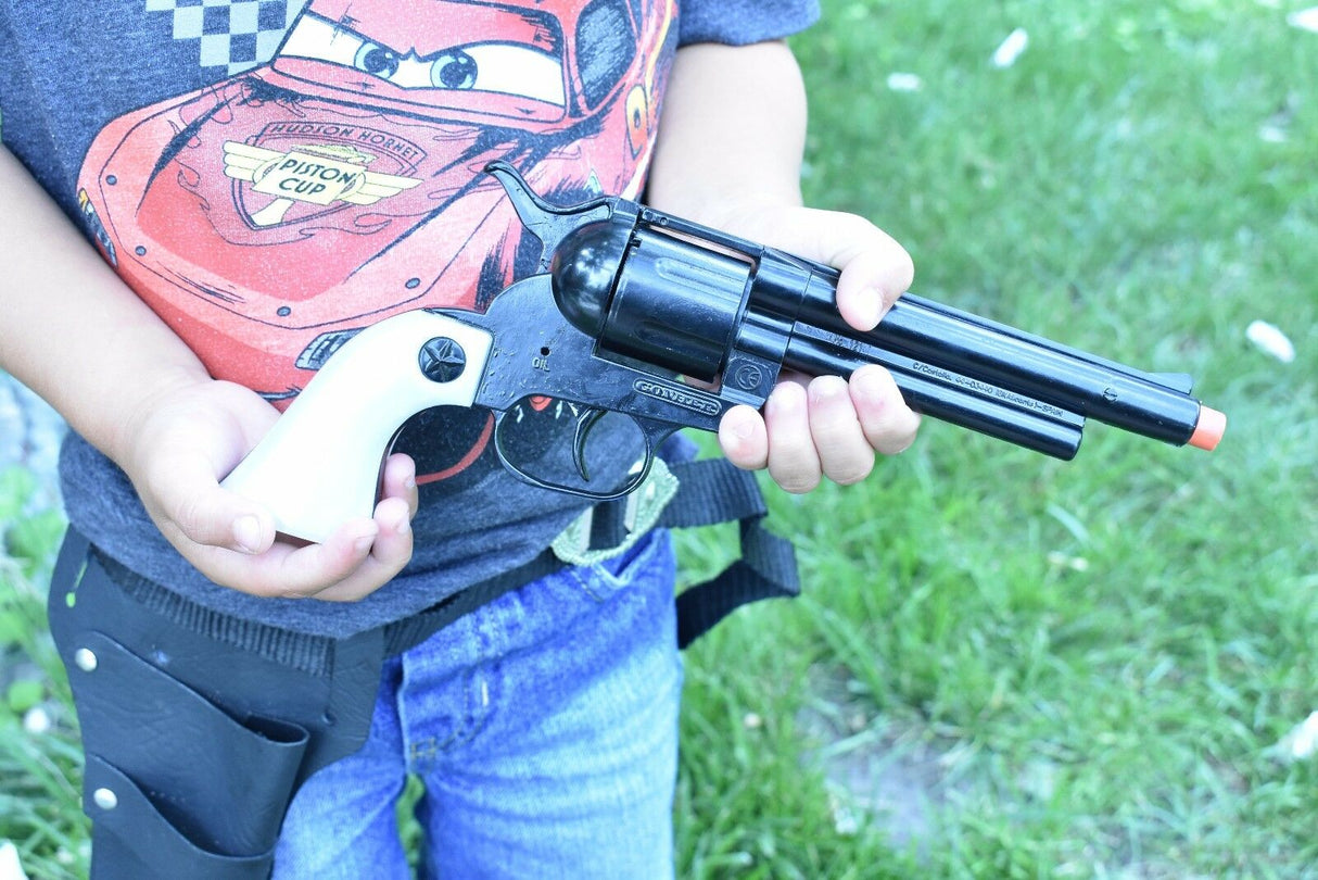 Child holding a black toy revolver against a green, grassy background for Parris Toys 4708B