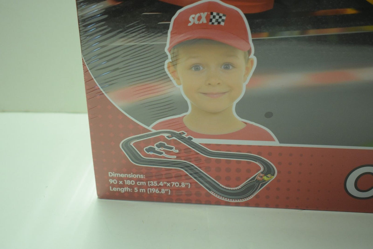 Race track box art featuring a smiling child and product dimensions for SCX Compact C10125X5U0
