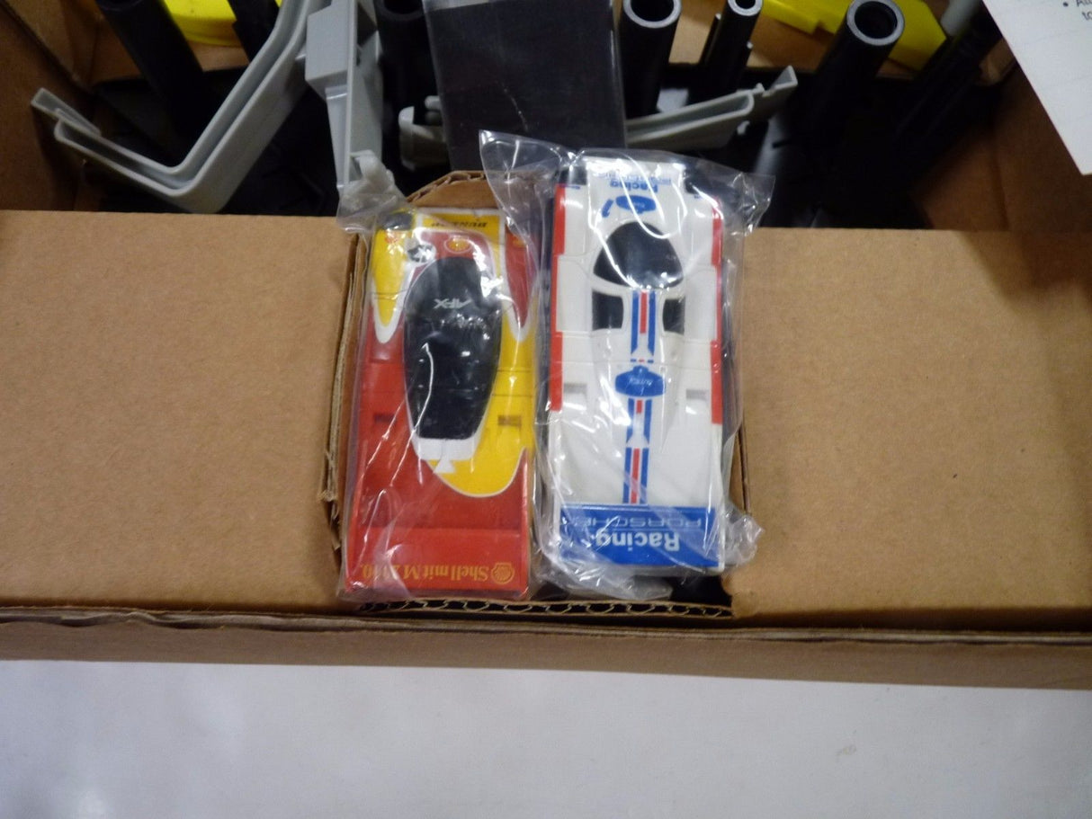 Two slot car race cars, one red/yellow and one white/red, in clear packaging for Aurora / AFX / Tomy 9115M
