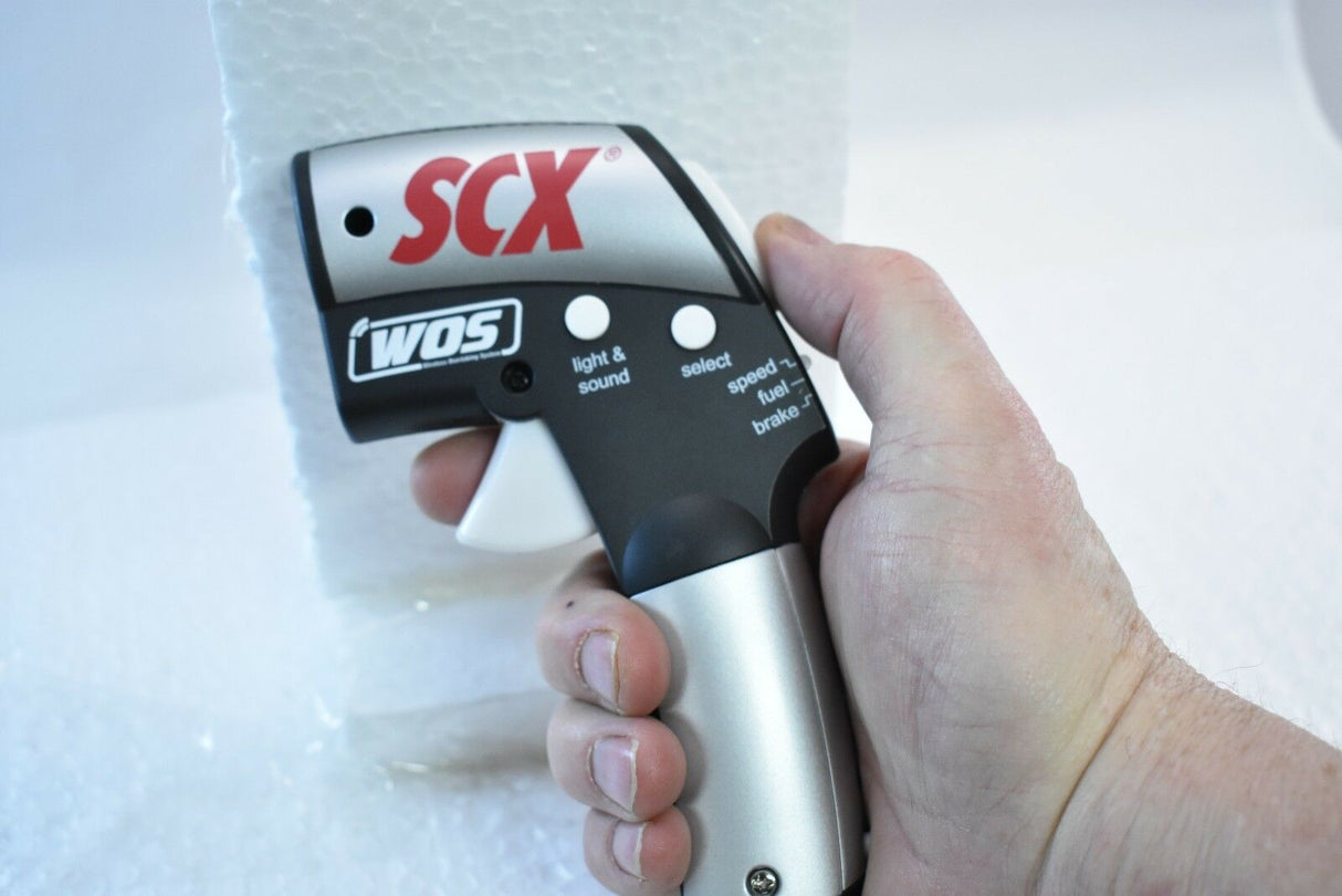 Hand holding a wireless throttle control with speed and fuel indicators for SCX WOS W101206X3U0