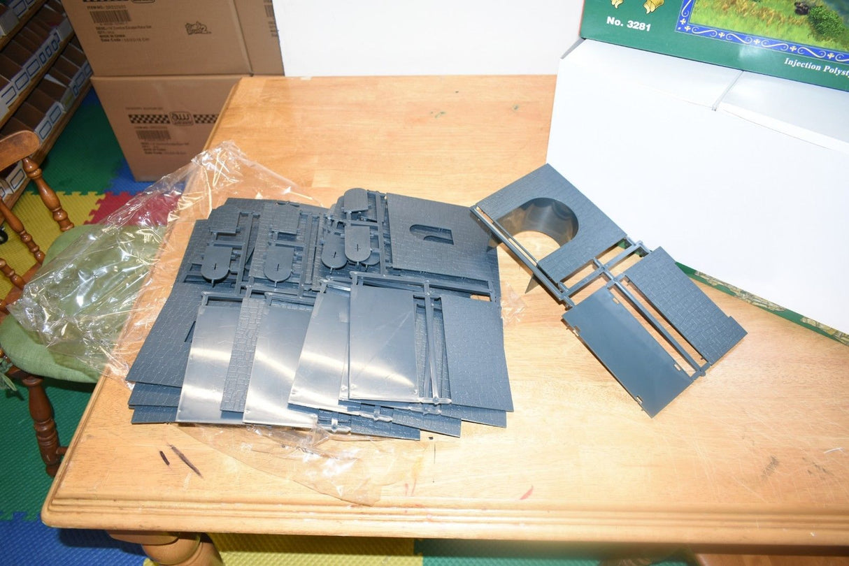 Plastic model parts for a castle, laid out on a wooden table for IMEX IMX3281