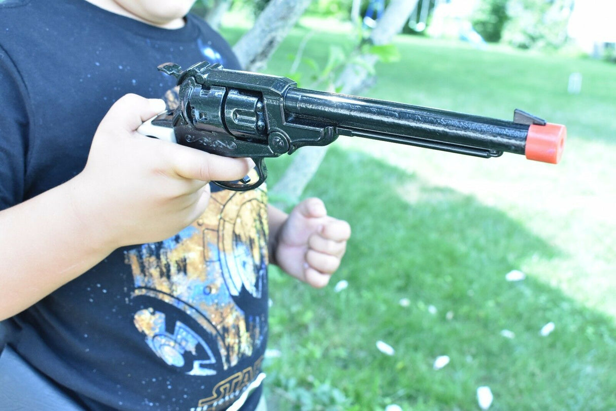 Child holding a black toy revolver with an orange tip outdoors for Parris Toys 0652