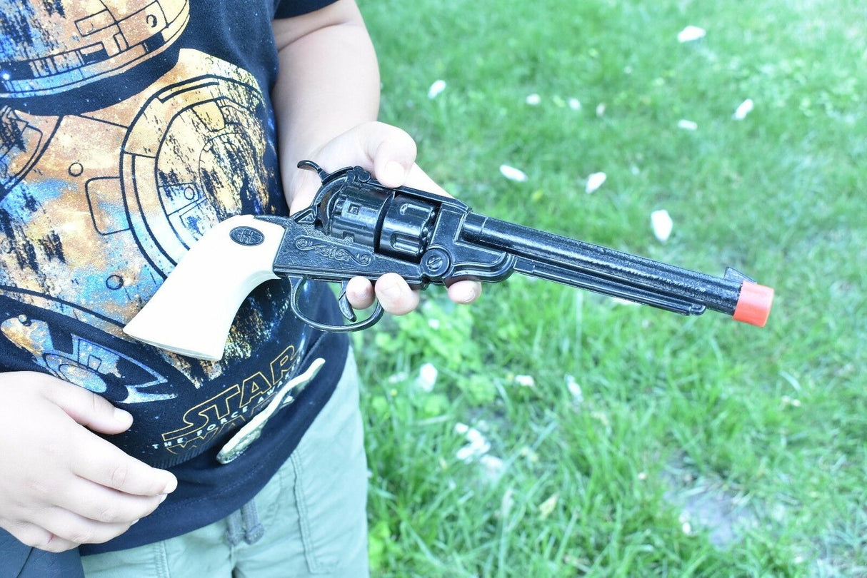 Child holding a black toy revolver with a white grip against green grass for Parris Toys 0652