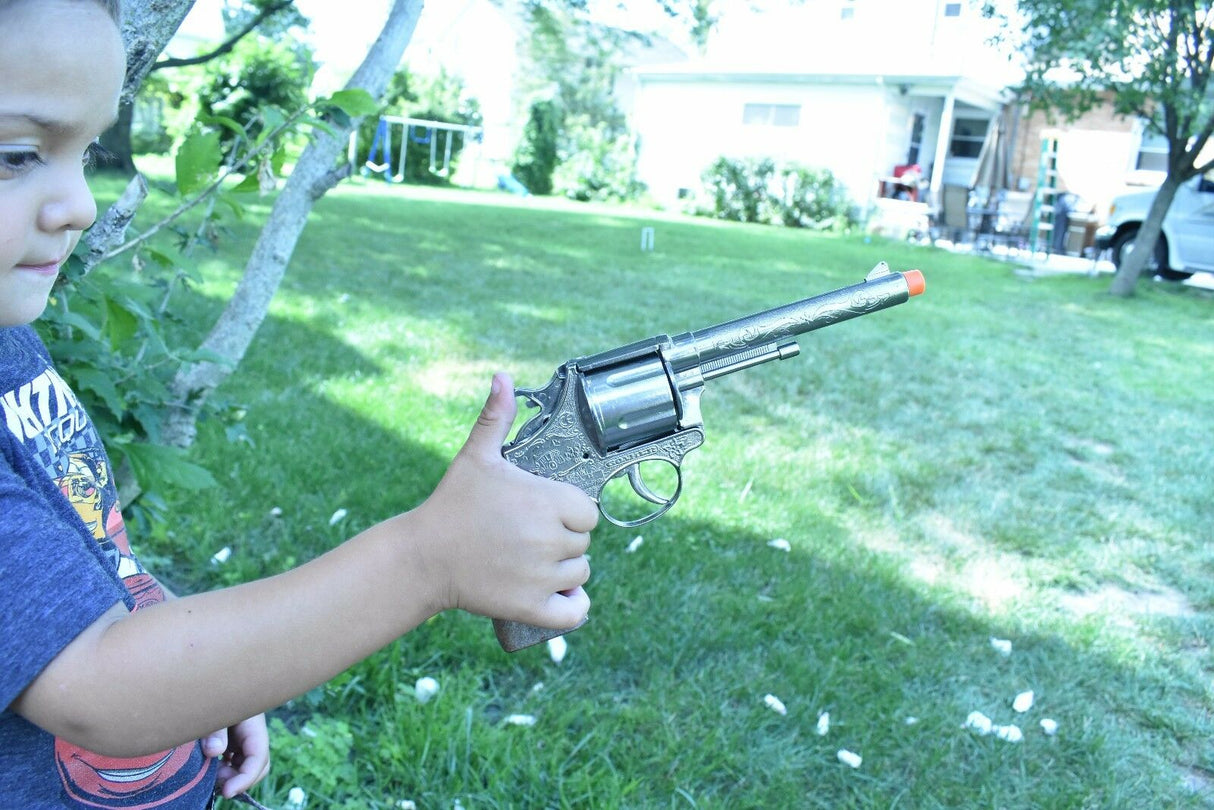 Boy holding a toy pistol and holster set outdoors on green grass for Parris Toys 4711, side view