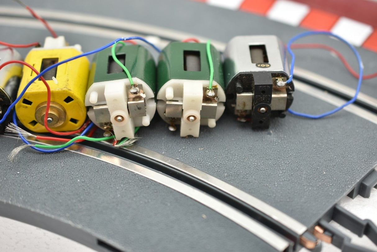 Assortment of small electric motors with wires laid on a gray surface for Mabuchi 8-Motors