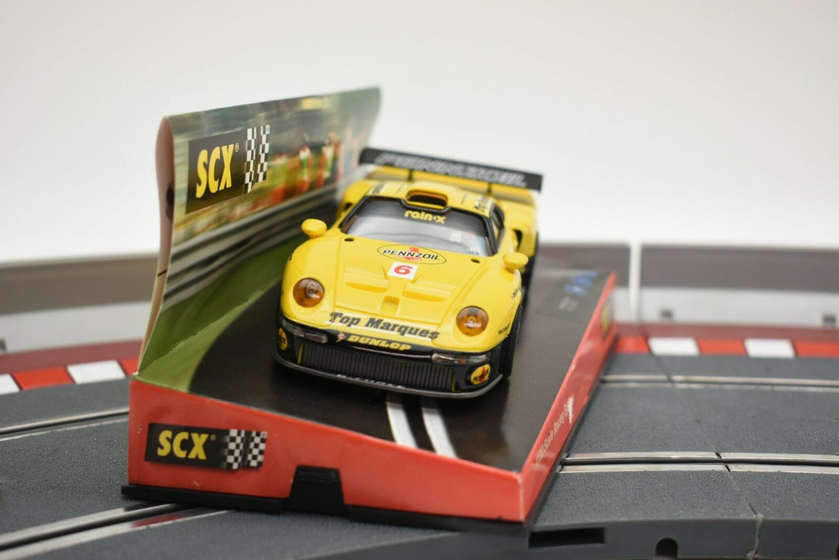 Yellow Porsche 911 GT1 race car on its display base for SCX Analog 60150
