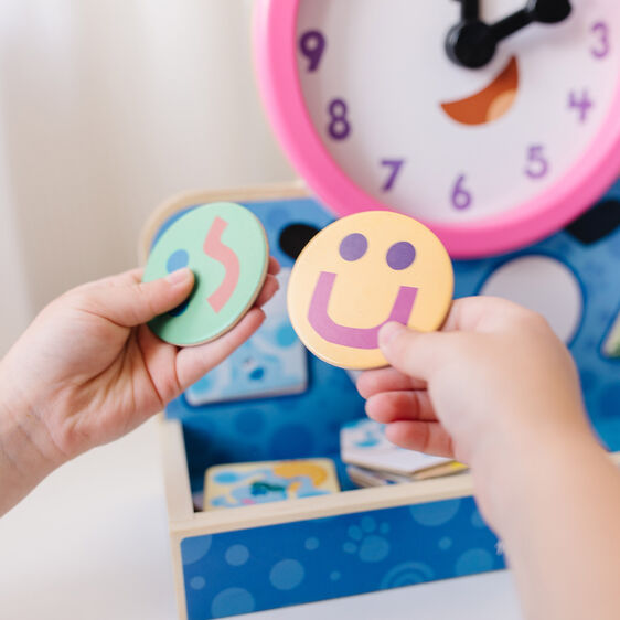 Hands interact with colorful, magnetic clock pieces on a wooden toy for Melissa and Doug 33014