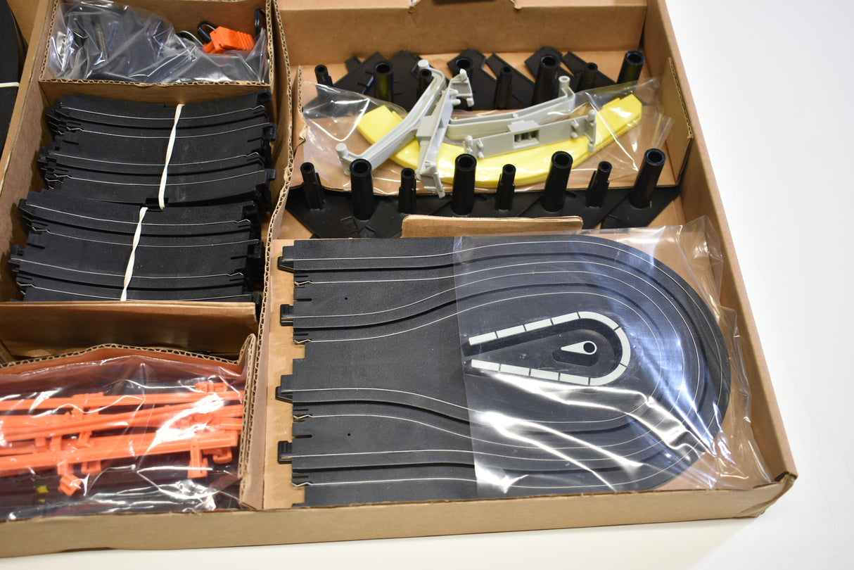 Slot car set components: track pieces, cars, and accessories in a box for Tomy AFX AURORA 9114M
