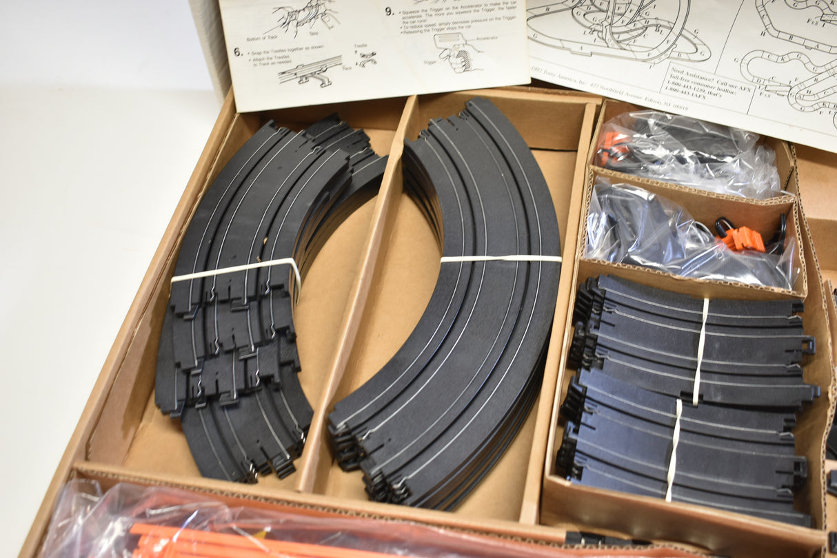 Curved black slot car track pieces and instructions in an open box for Tomy AFX AURORA 9114M