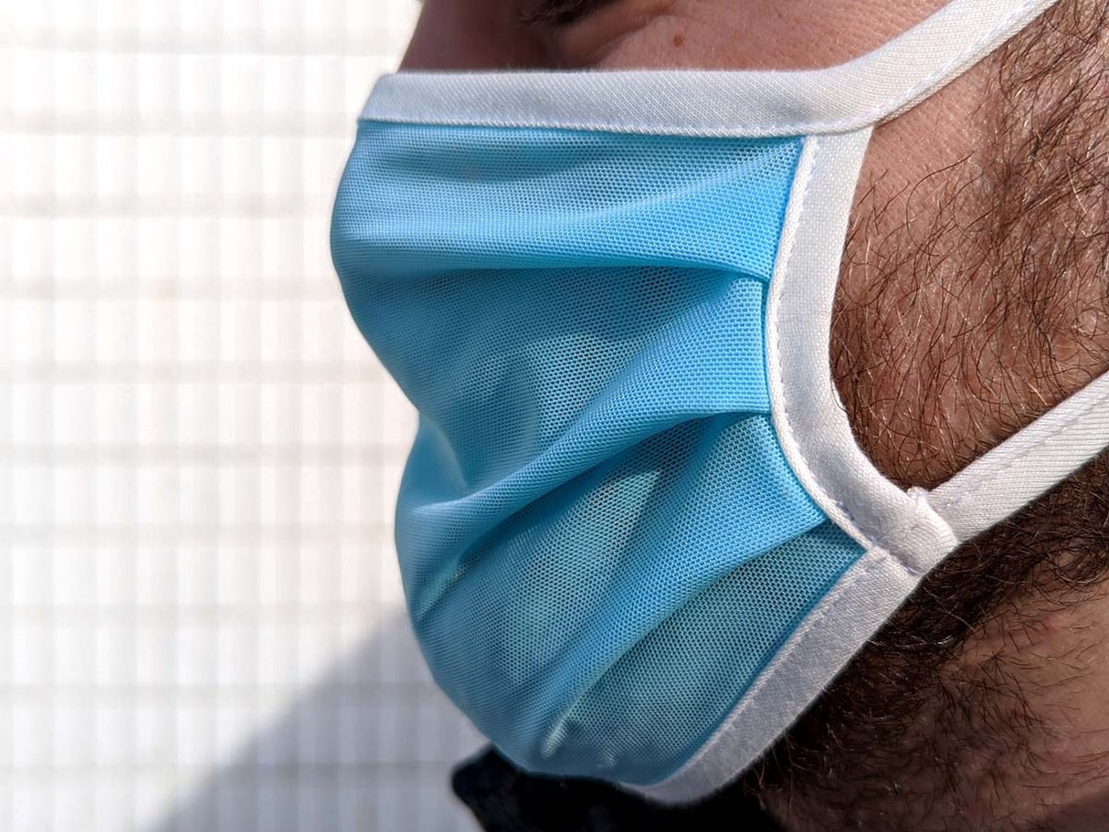 Light blue disposable face mask worn over a person's nose and mouth for Fake Mask USA