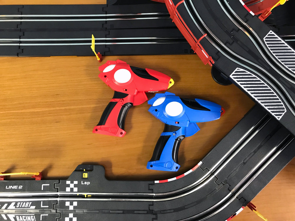 Red and blue remote control race cars on a black slot car track for EXCLUSIVE JLRS001