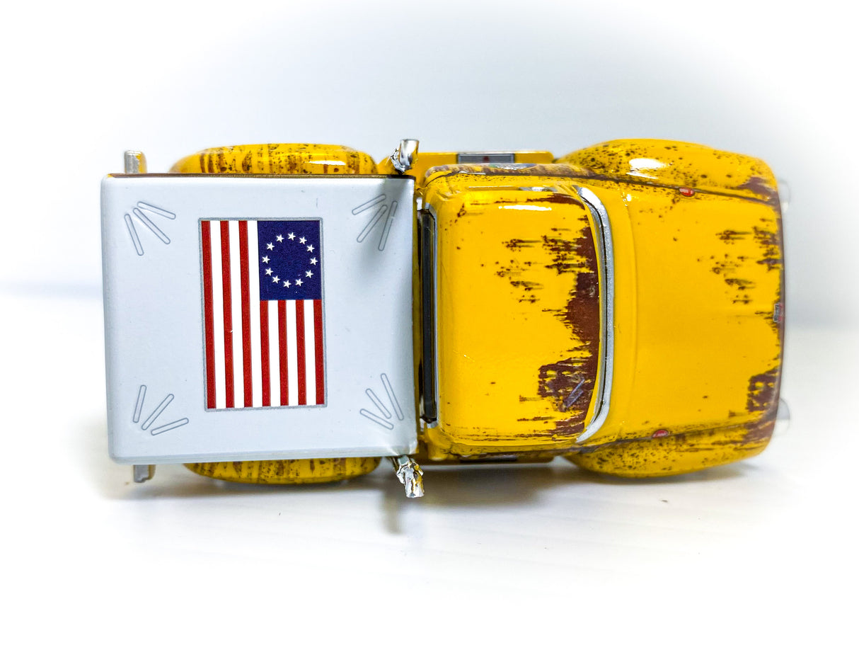Yellow toy delivery truck with a side panel displaying the American flag for Auto World