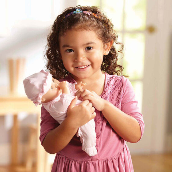 Smiling girl holding a baby doll, ready for playtime for Melissa and Doug 4881