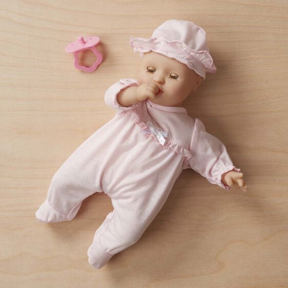 Doll in pink sleeper and bonnet lying on wood surface for Melissa and Doug 4881