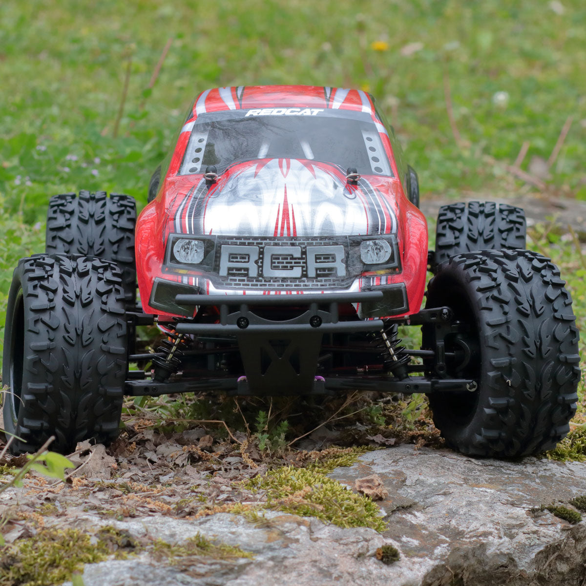 Red monster truck on rocks with large off-road tires for RedCAT VOLCANOEP-94111-BS-24