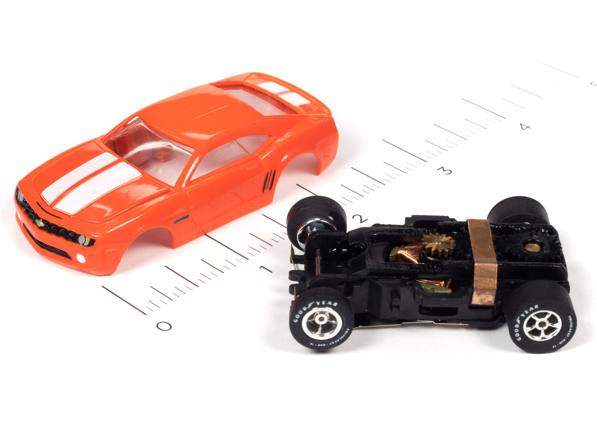 Orange slot car muscle car next to a black, vintage-style slot car on a ruler for Auto World SC354