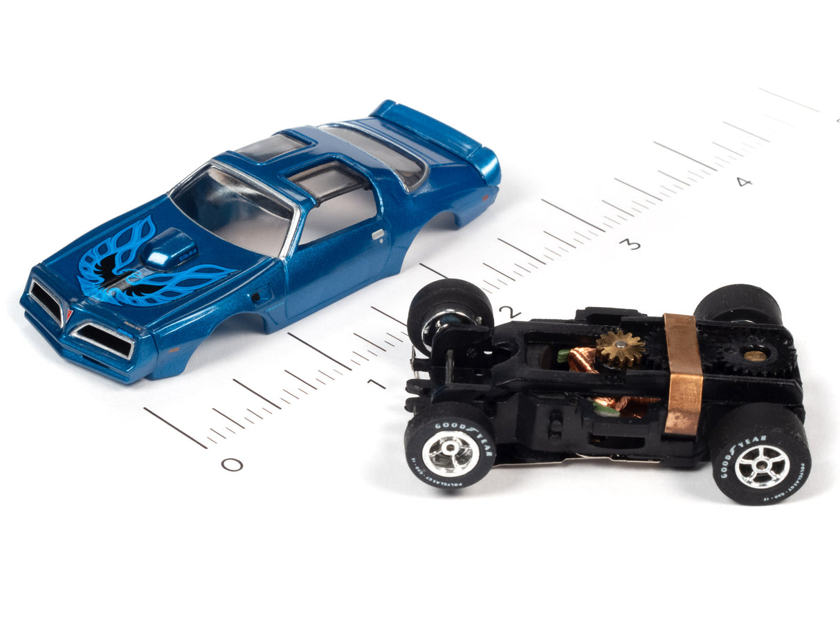 Blue slot car muscle car and black slot car on a ruler for Auto World SC354, rear view