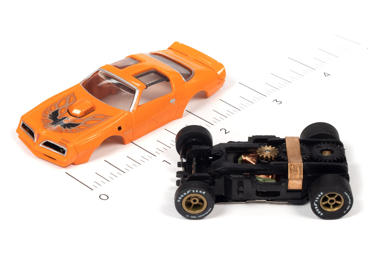 Orange slot car muscle car and black race car on a ruler for Auto World SC354