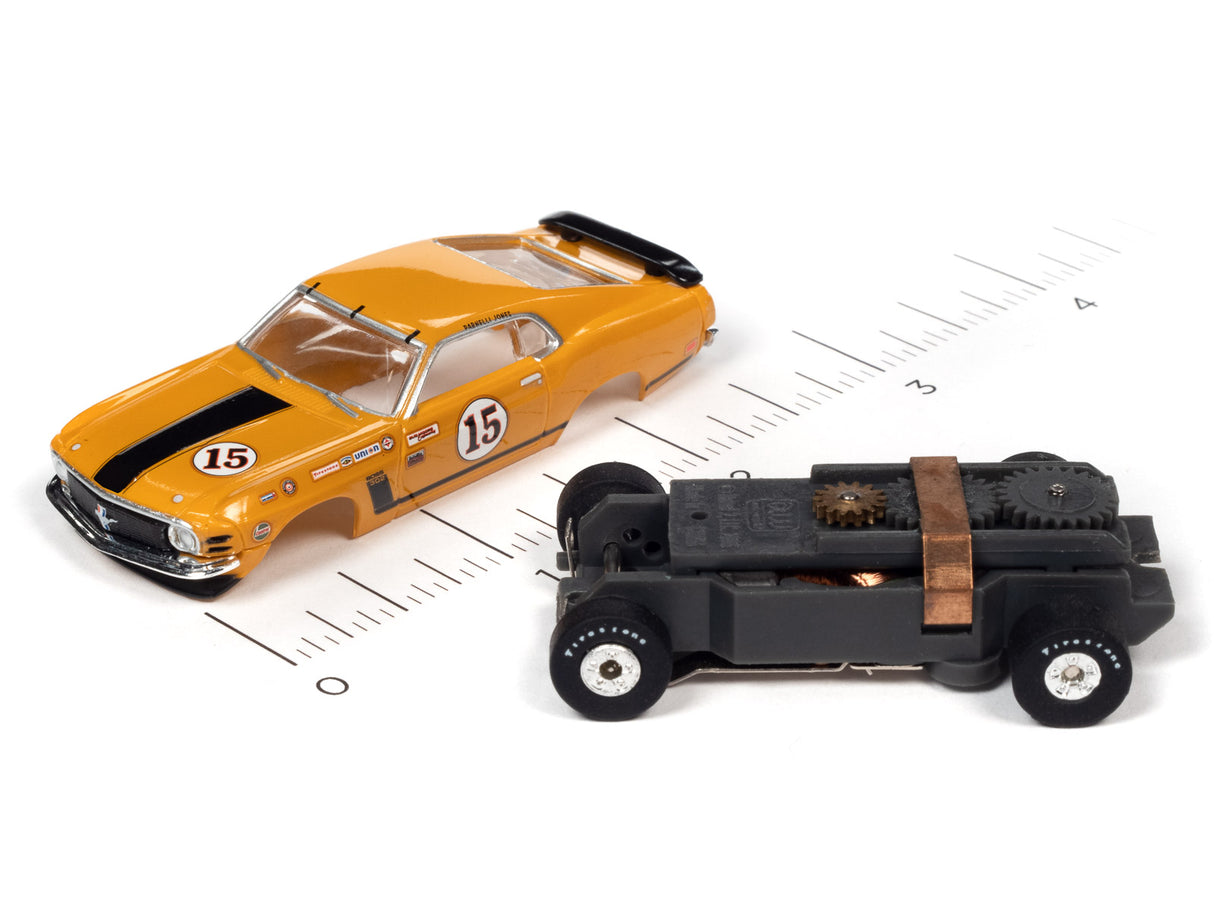 Yellow Trans Am toy car and black toy vehicle on a ruler for Auto World SC357