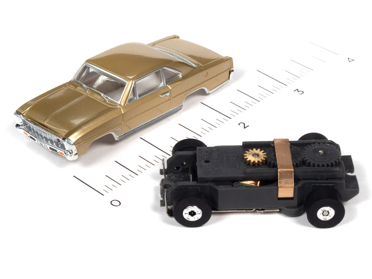 Two slot cars, a gold sedan and a black, mechanical-style vehicle, on a ruler for Auto World SC360