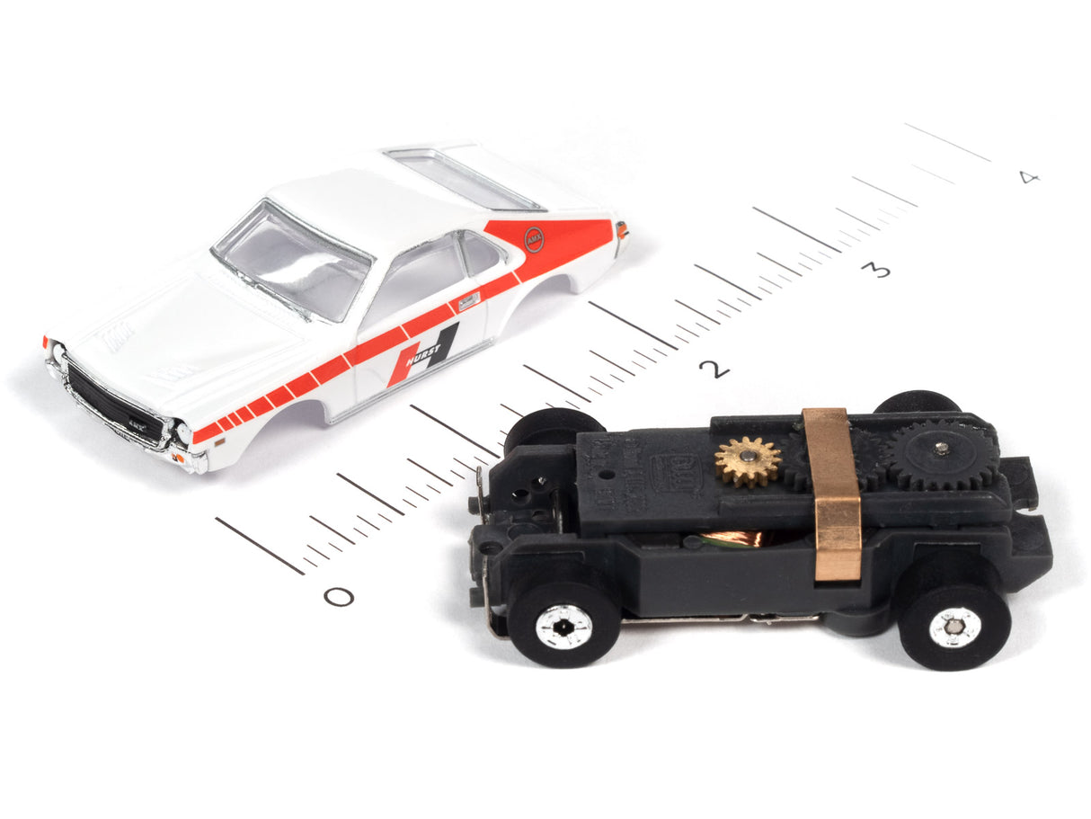 Two slot cars, a white sedan and a black, mechanical-looking vehicle, on a ruler for Auto World SC360