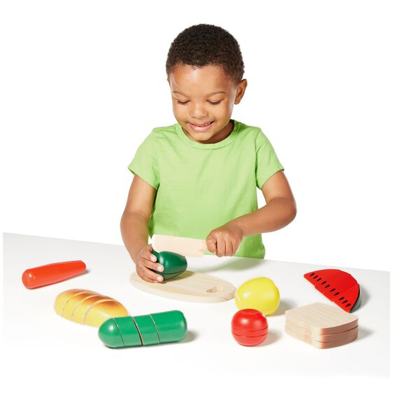 Child plays with wooden food set, simulating cutting and preparing meals for Melissa and Doug 487