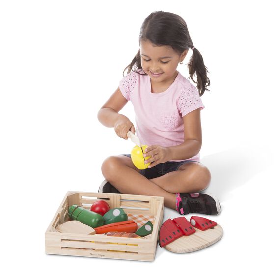 Girl plays with wooden play food, cutting pretend vegetables on a cutting board for Melissa and Doug 487