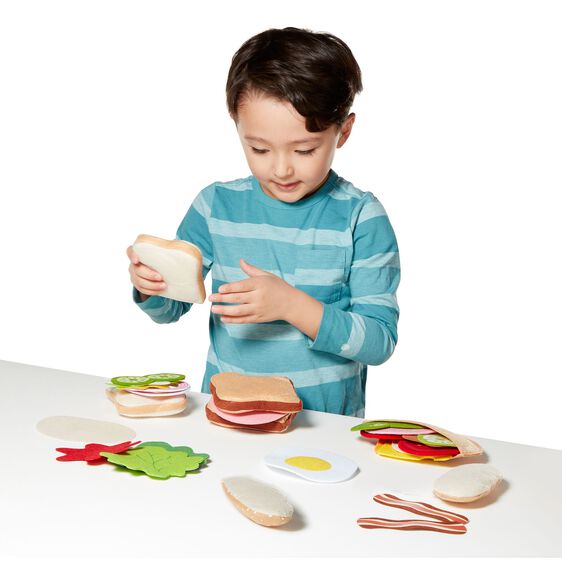Boy plays with felt play food, assembling a pretend sandwich set for Melissa and Doug 3954