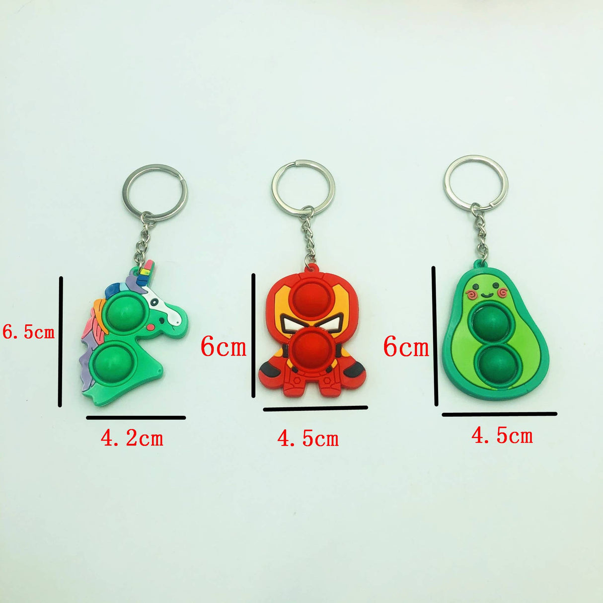 Three pop-it keychain fidget toys: unicorn, mask, and avocado for Faire FH2928