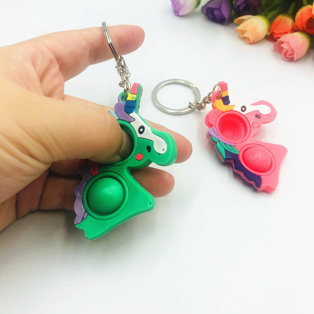 Green and pink pop-it keychain fidget toys held in a hand for Faire FH2928