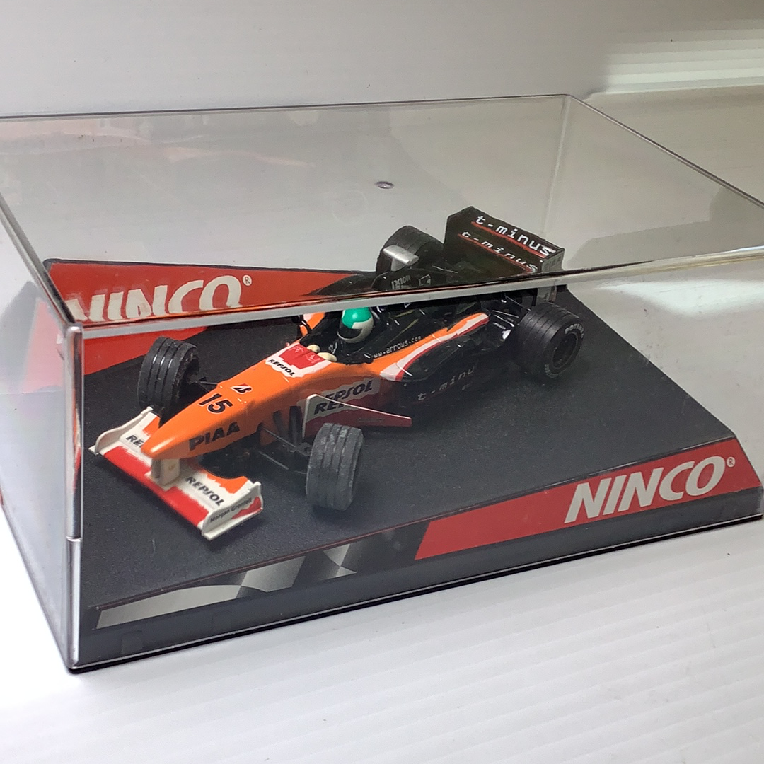 Slot car race cars, one orange and one black, displayed in a clear box for Ninco 50212