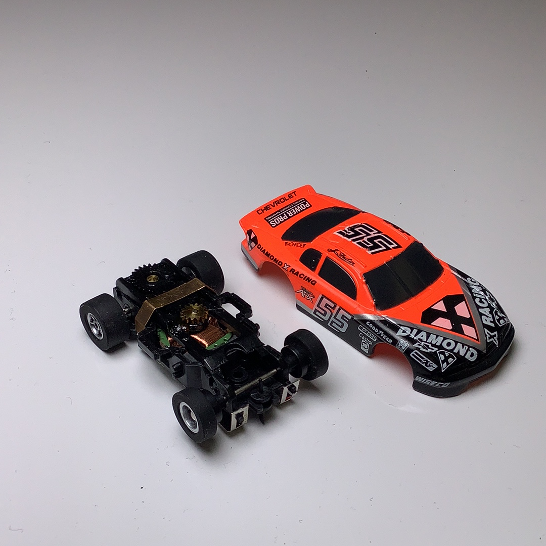Black and orange race car and chassis model on white surface for Aurora / AFX / Tomy 9870