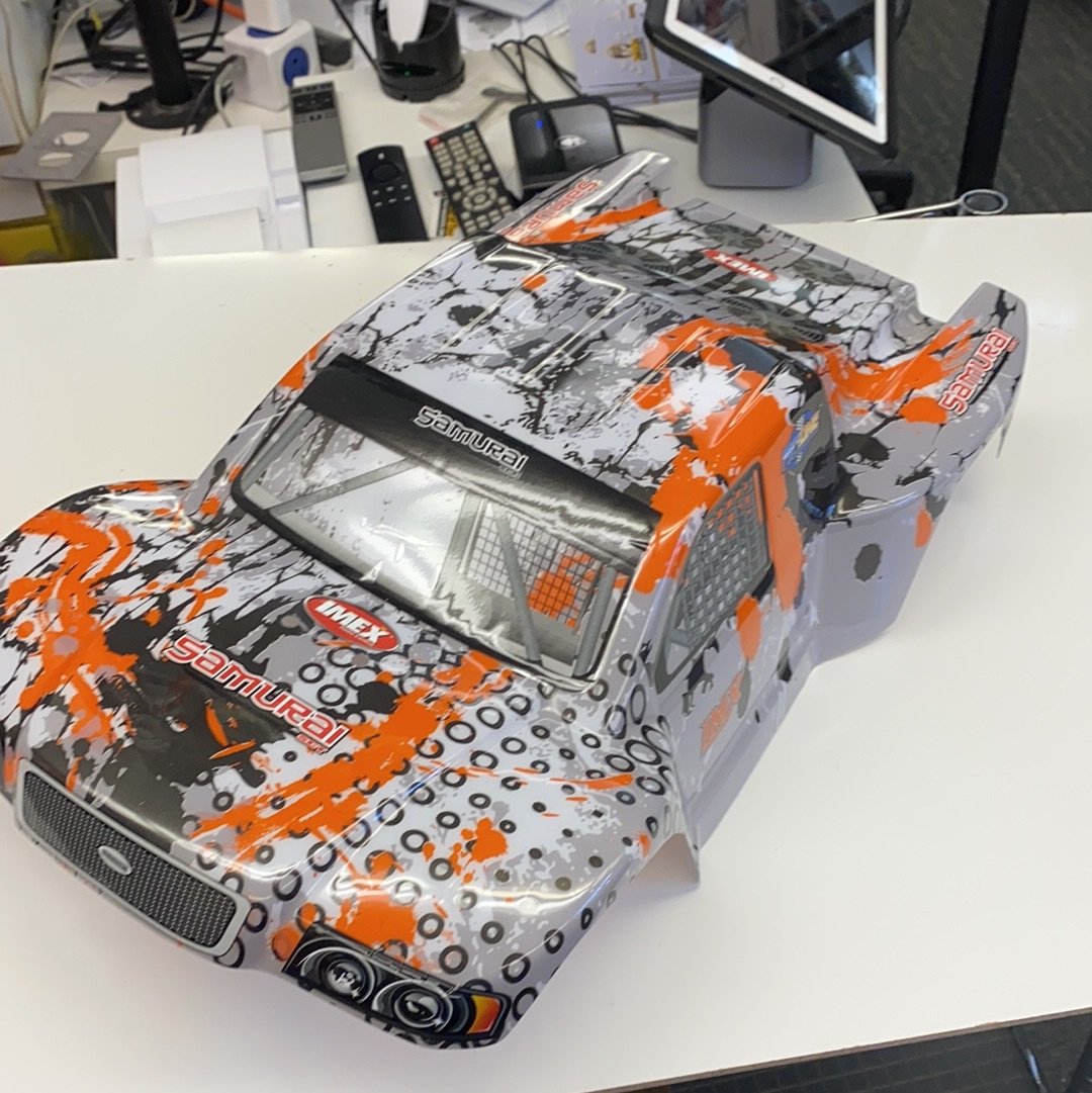 Die-cast model car with orange and black camouflage pattern for IMX18468, front view