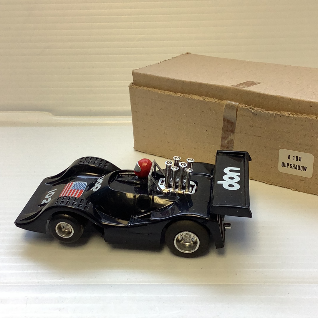 Black model race car, UOP Shadow, next to its open box for REH Polistil A.108