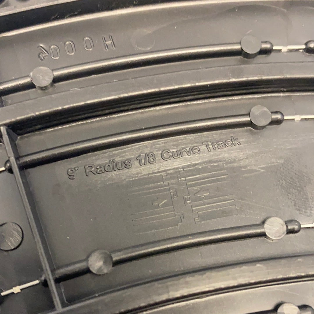 Black model train track section showing "9" Radius 1/8 Curve Track" marking for Auto World H0004