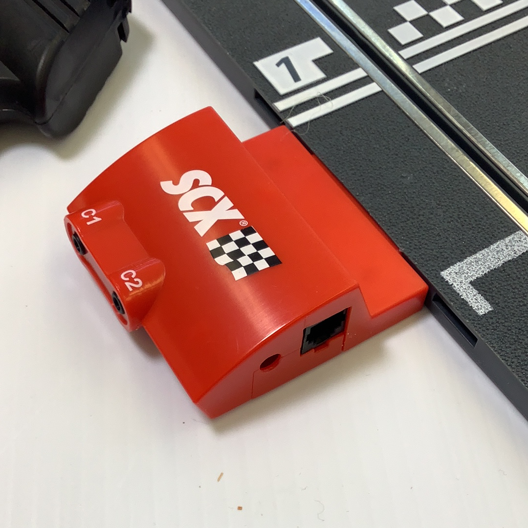 Red throttle controller with two ports and a black unit nearby for SCX A4000