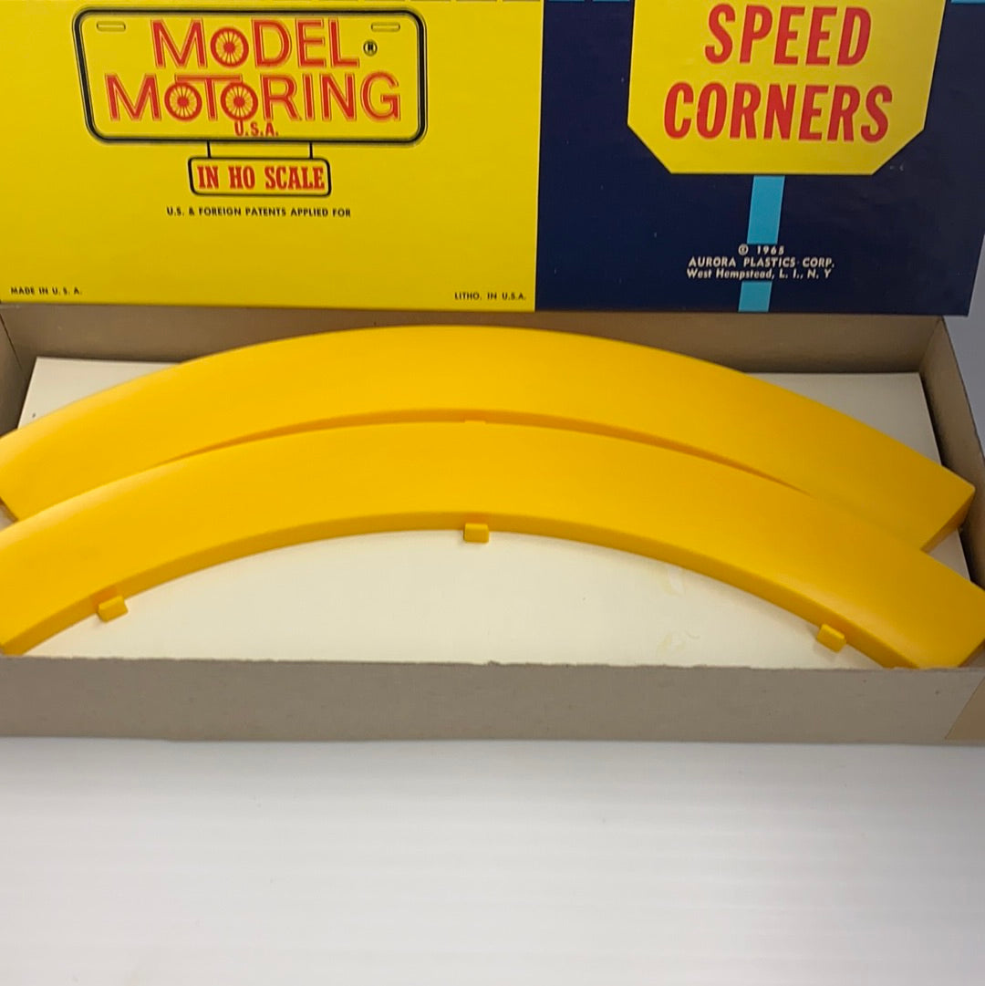 Yellow plastic speed corner track pieces in an open box for Aurora Model Motoring 1598