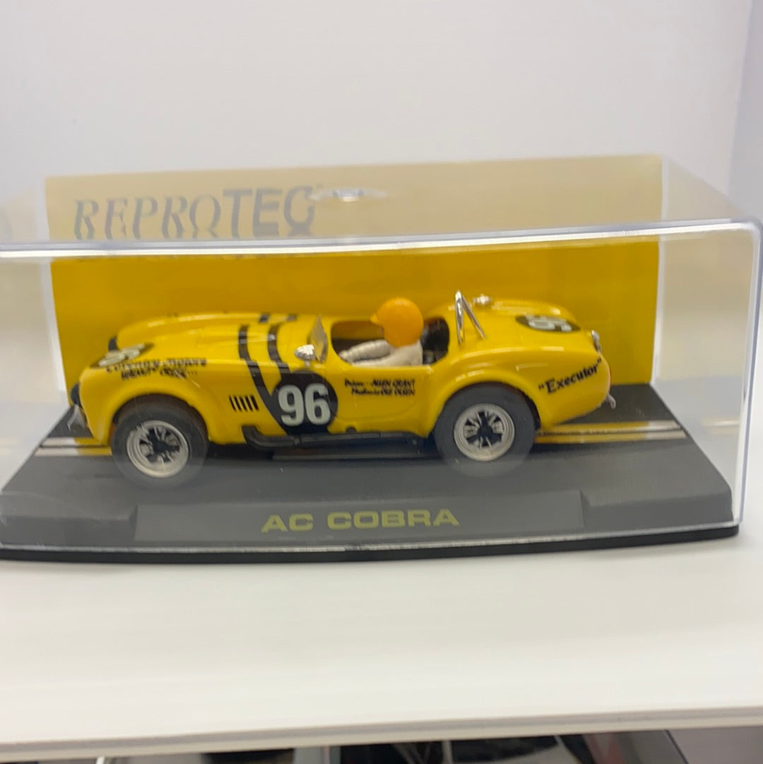 Yellow 1964 AC Cobra slot car on a display base for REPROTEC RT/1964, rear view