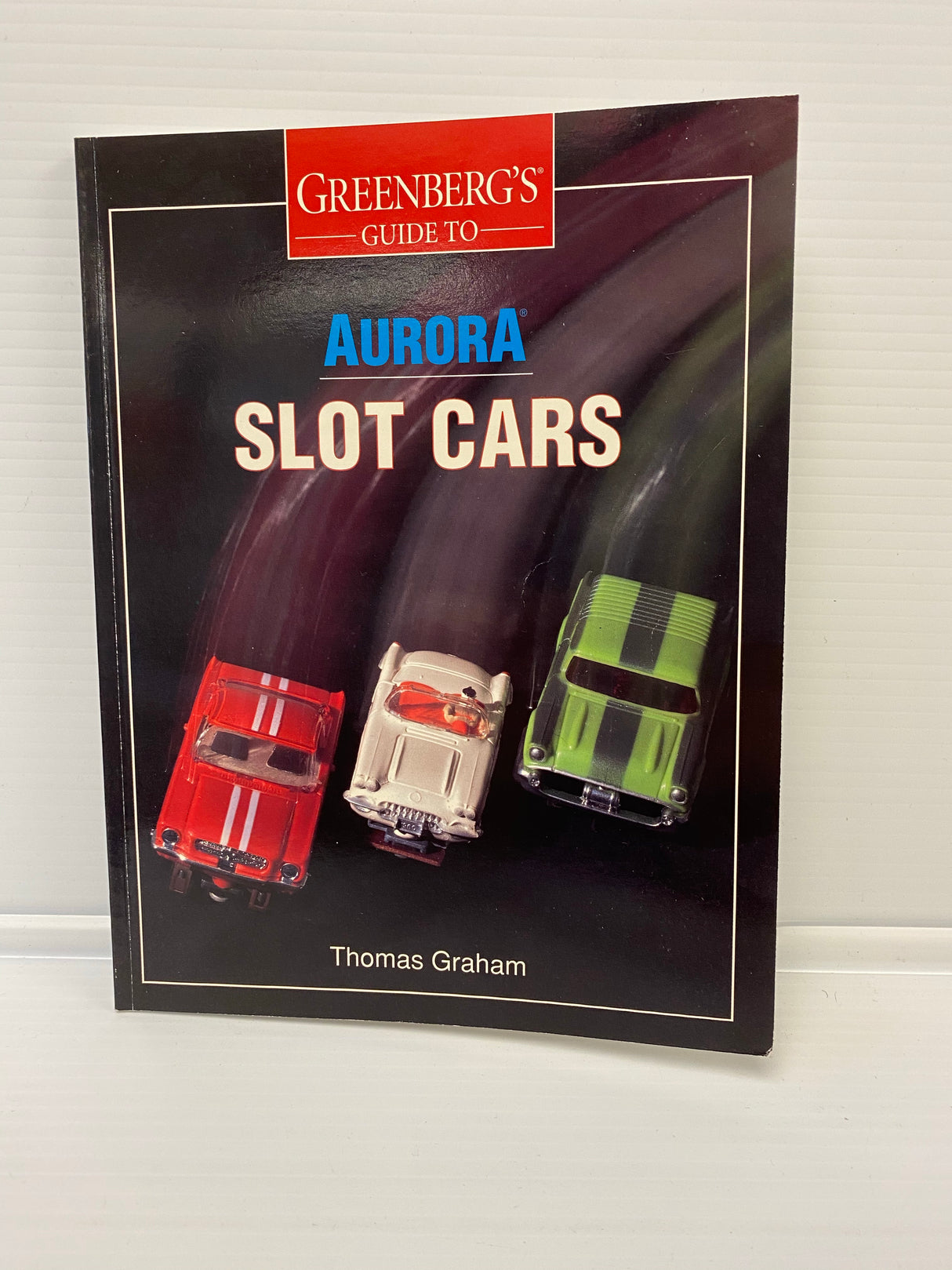 Guidebook featuring three slot cars: red, silver, and green for Thomas Graham 9000