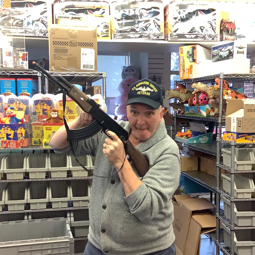 Man holding an AK-47 assault rifle in a store aisle for Gonher 1135/6, rear view