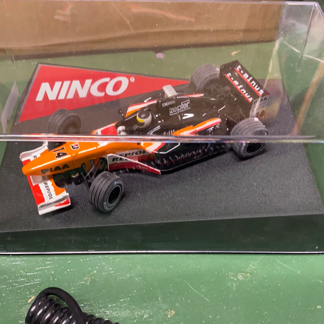 Two slot car race cars, one orange and one black, displayed in a case for Ninco 50211