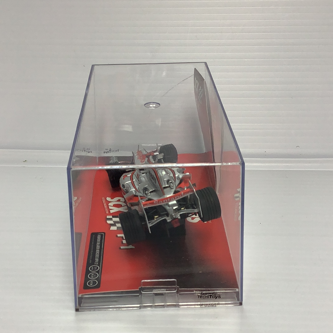 Red slot car in clear plastic box, representing a McLaren F1 race car for SCX 62570